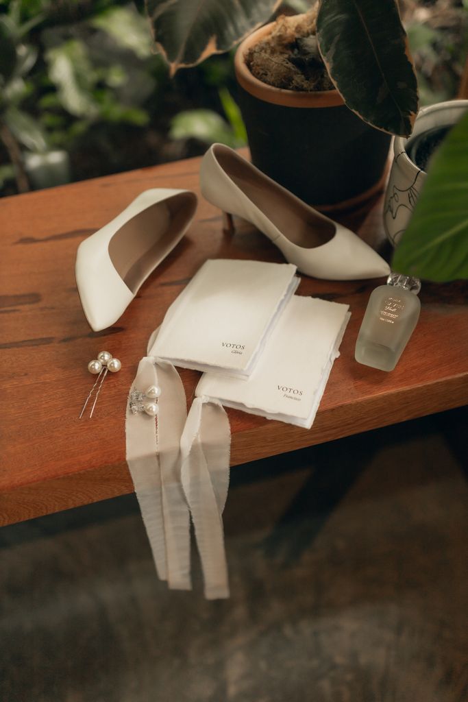 Flat lay of bridal accessories with shoes, veil, and perfume on a wooden table, perfect for wedding preparations.